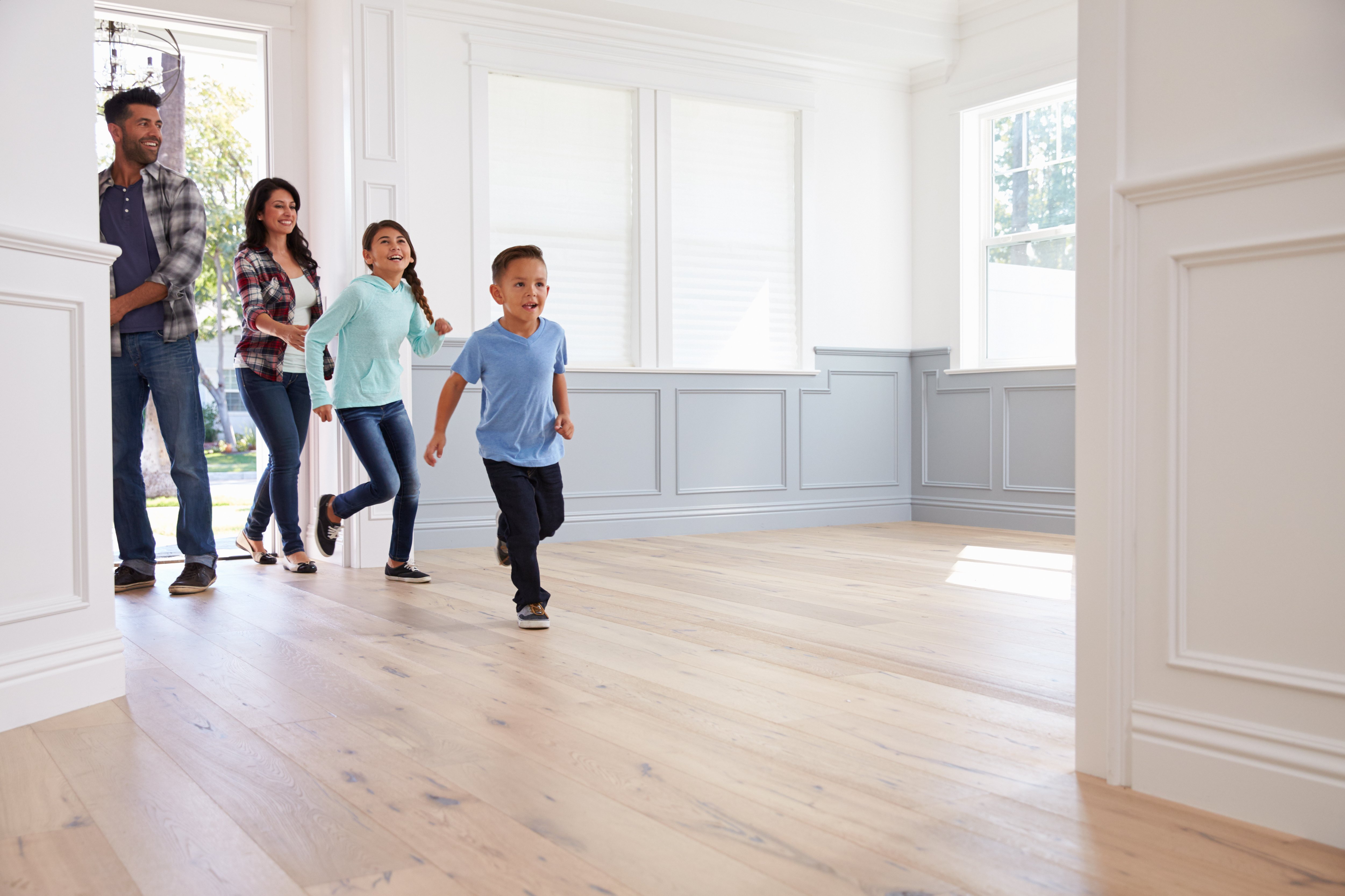 young family entering empty house with new floors